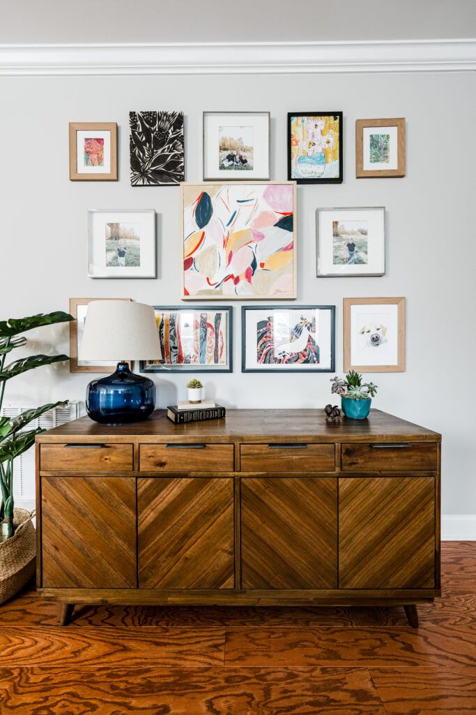 Wood chevron credenza under a colorful framed gallery wall, by Hayden Home Studio in Weddington, NC