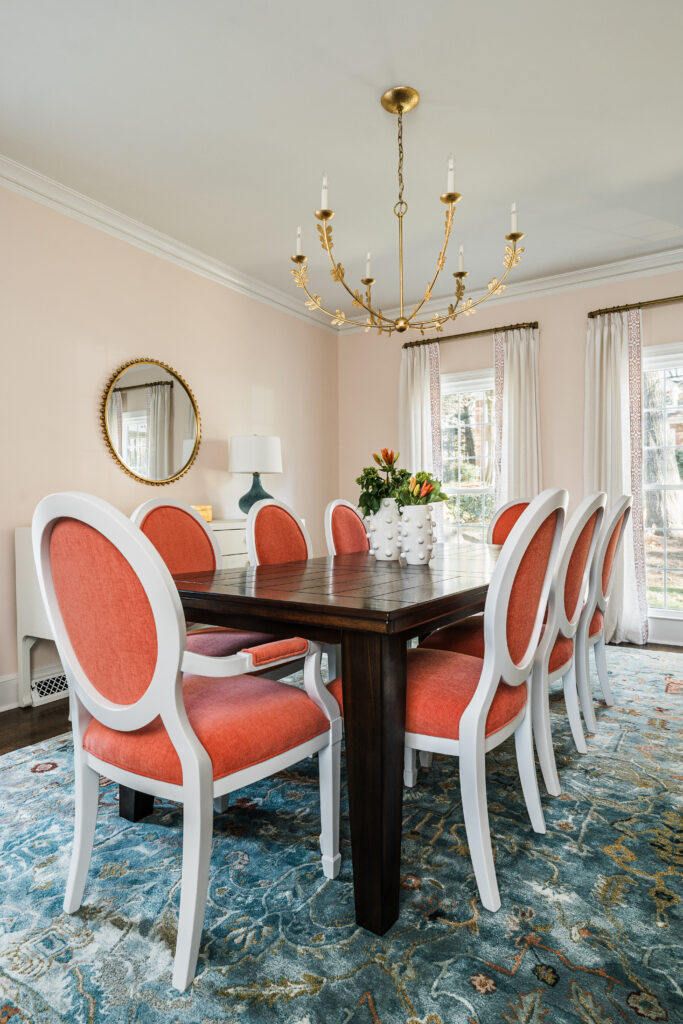 Dining room with coral oval-back chairs, a gold floral chandelier, and blush walls, by Hayden Home Studio in Park Crossing, Charlotte NC
