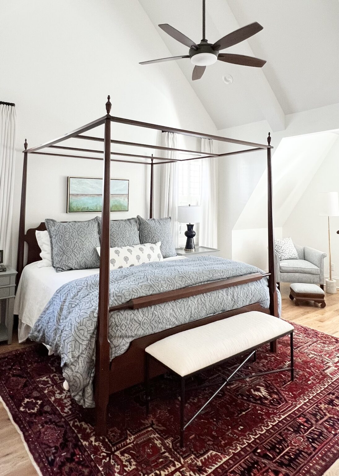 Primary bedroom with a four-poster canopy bed, blue bedding, and a red patterned rug, by Hayden Home Studio in Plaza Midwood, Charlotte NC