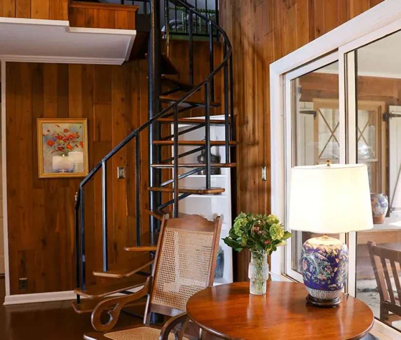 Black spiral metal staircase in a hardwood-floored room designed by Hayden Home Studio, Charlotte NC
